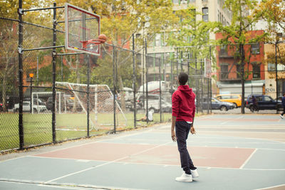 Full length of student playing at basketball court in city