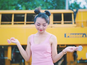 Woman holding lollipop while standing against building