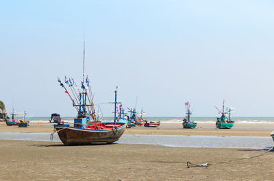 Fishing boats moored on beach against clear sky