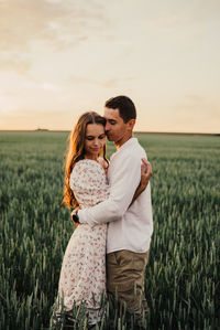 Young woman standing on field against sky