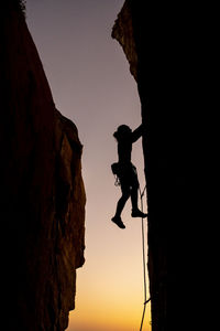 Beautiful view to silhouette of man climbing during sunset