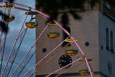 Low angle view of illuminated ferris wheel against building