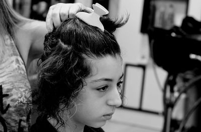 Midsection of mother holding daughter hair at home