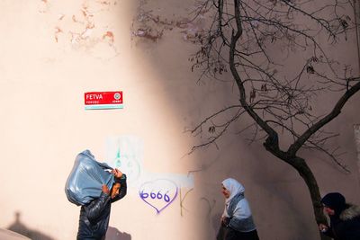 Rear view of people standing against wall