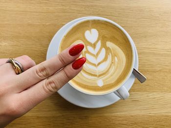 Midsection of woman holding coffee cup on table