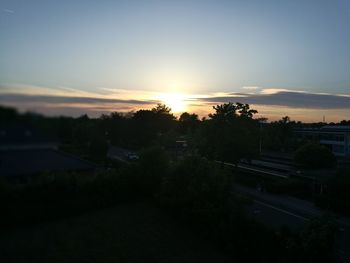 Trees against sky during sunset in city