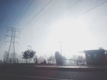 Power line against cloudy sky