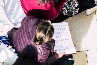 High angle view of girl sitting on book