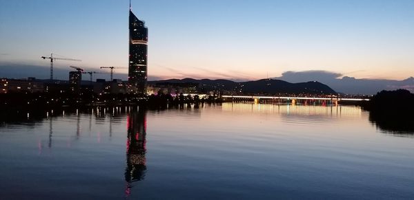 Reflection of illuminated buildings in lake at sunset