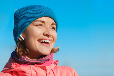 Portrait of smiling woman against blue sky