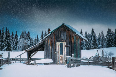 Hut on snow covered land against sky