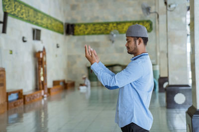 Side view of man praying at mosque