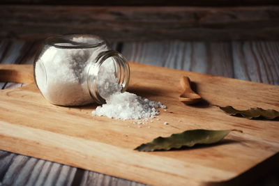 Bay leaf and salt in glass container on wooden background