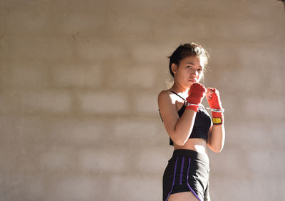 Young woman standing against wall