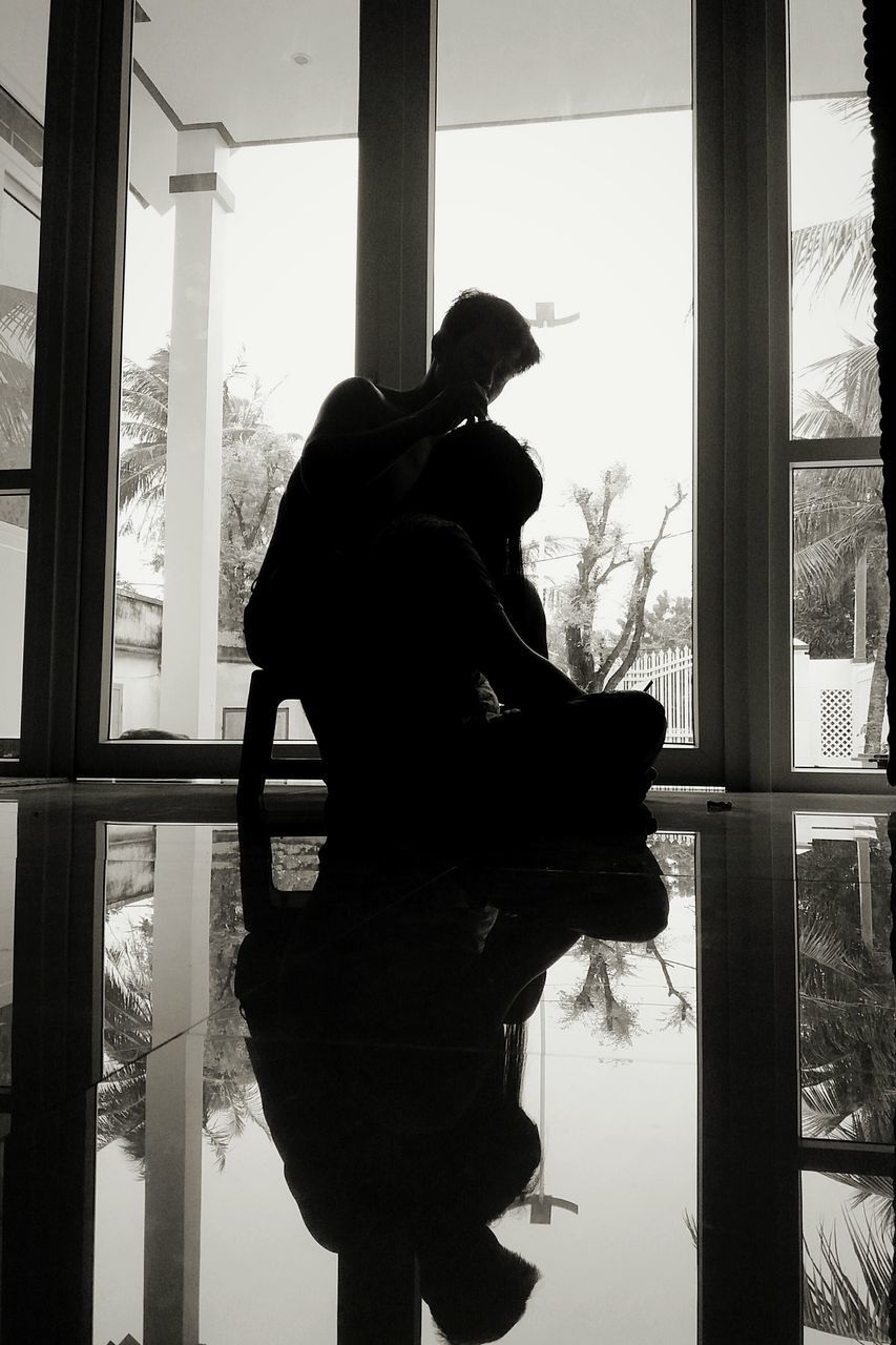 SILHOUETTE COUPLE STANDING BY WINDOW