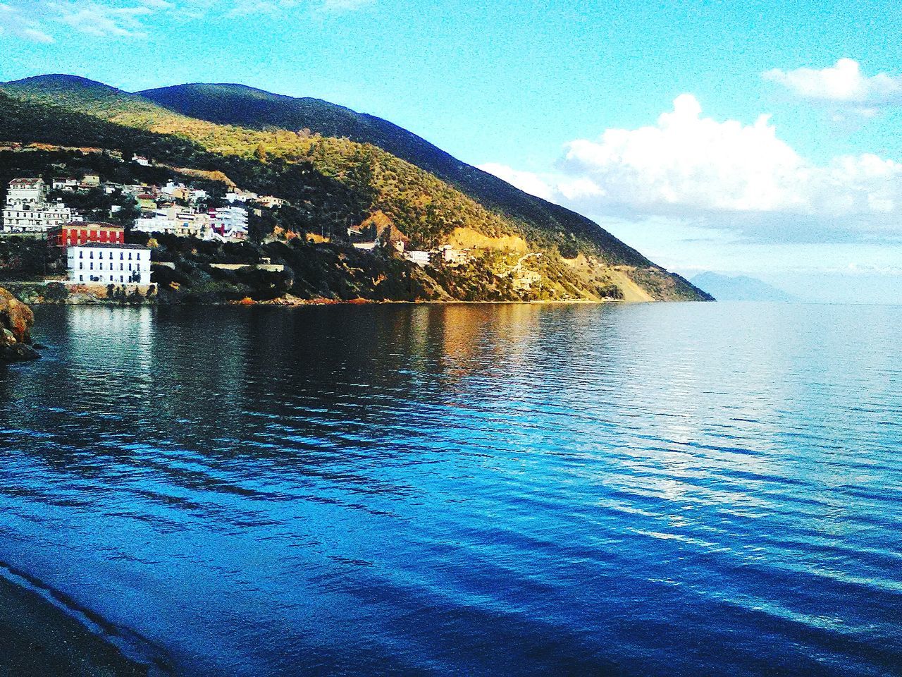 water, building exterior, sea, architecture, waterfront, built structure, blue, sky, mountain, scenics, house, tranquil scene, beauty in nature, nature, tranquility, residential structure, town, residential building, rippled, residential district