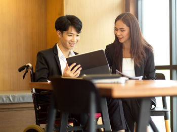 Young woman using phone while sitting on table