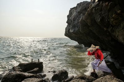 Asian woman with traditional clothing standing on seashore