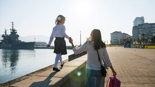 Rear view of mother with daughter walking in city