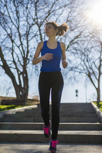 Portrait of a woman running on staircase outdoors in a park
