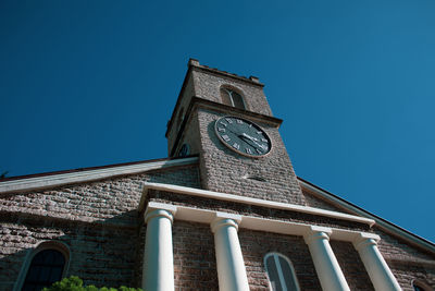 Low angle view of clock tower against clear blue sky