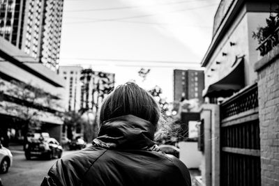 Rear view of man standing in city against sky