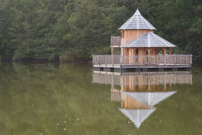 Built structure by lake against building. wooden building by lake. stilt house by lake 