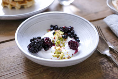 Close-up of yogurt with blackberries and pistachios in bowl at table