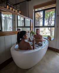 Rear view of woman sitting in bathtub