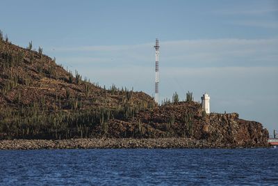 Lighthouse by sea against sky