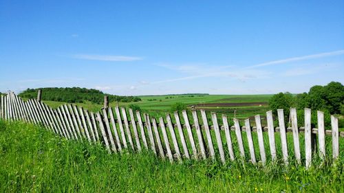 Fence on land against blue sky