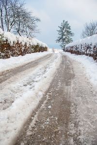 Surface level of snow covered road against sky