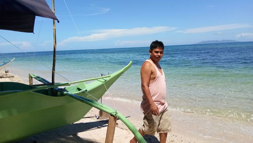 Portrait of man standing at beach against sky