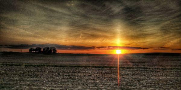 Scenic view of sea against cloudy sky during sunset