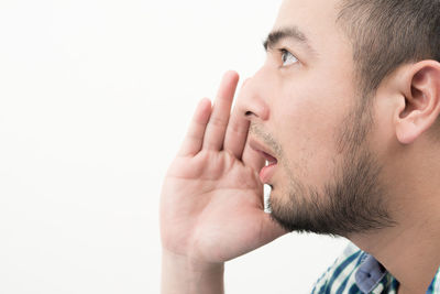 Side view of young man whispering over white background