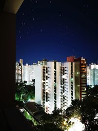 Buildings against clear blue sky at night