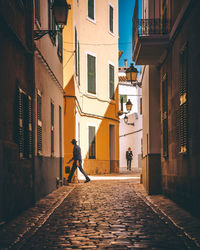 Rear view of people walking on street amidst buildings