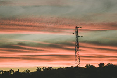 Low angle view of silhouette electricity pylon against romantic sky