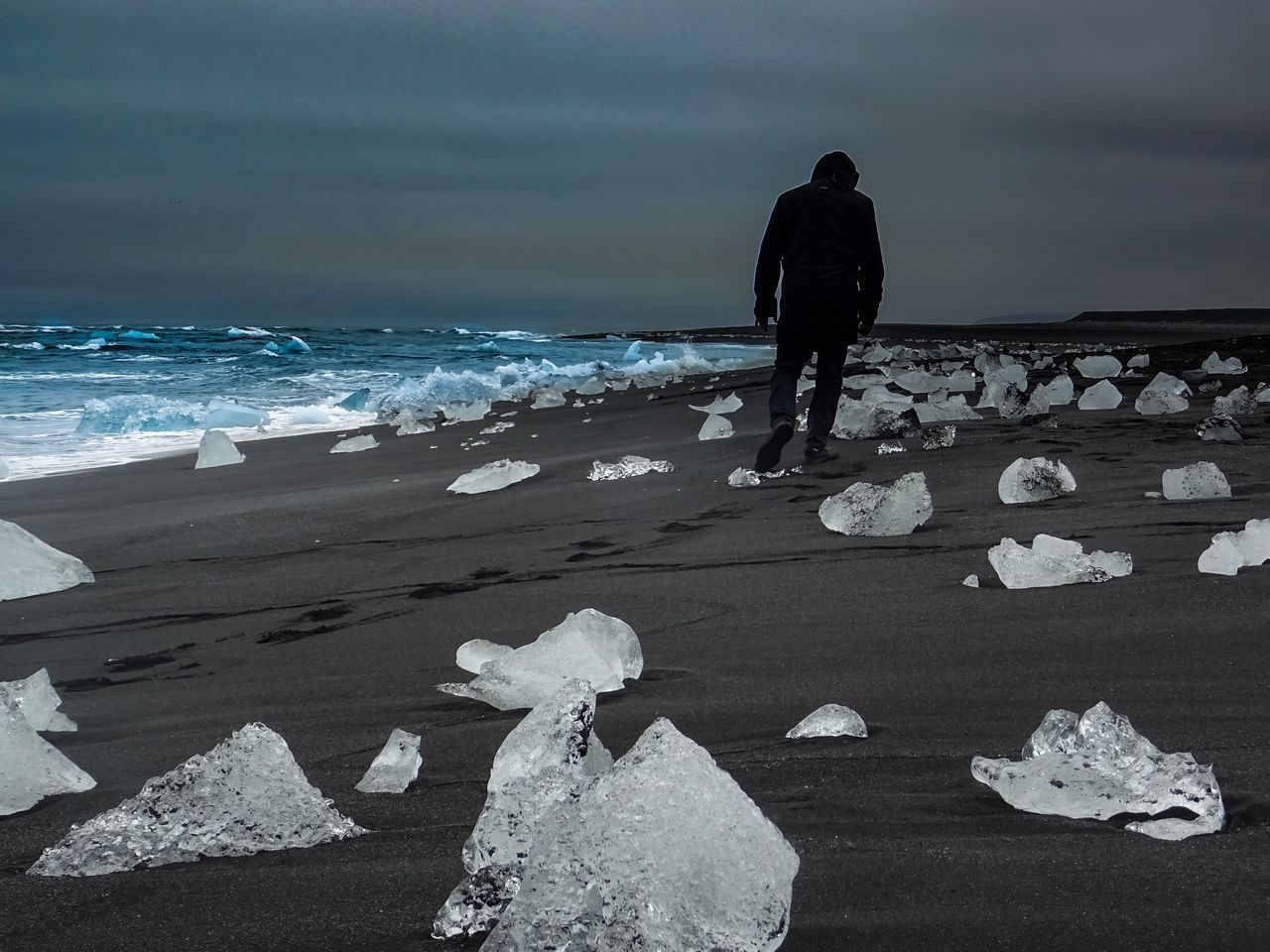 REAR VIEW OF MAN STANDING ON BEACH AGAINST SEA