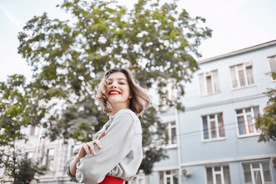 Portrait of a smiling young woman against building