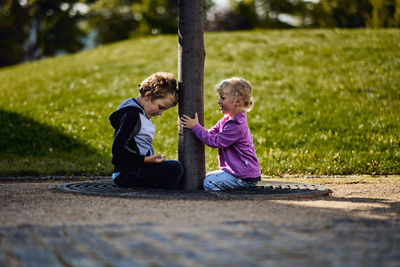 Side view of kids sitting on tree