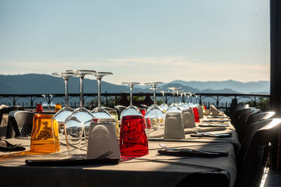 Row of wine glasses on table against sky on sunny day