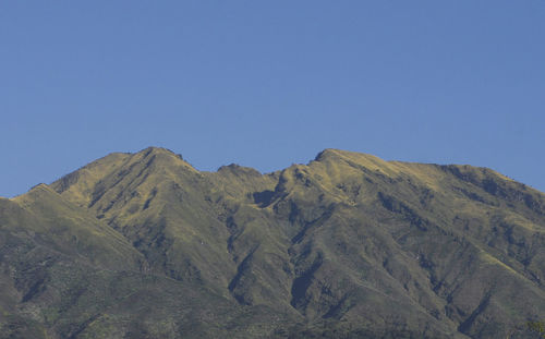 Scenic view of volcanic mountain against clear blue sky