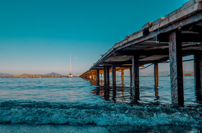 Pier over sea against clear blue sky