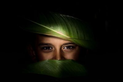 Close-up portrait of young woman against black background