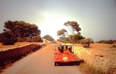 Car on road amidst field against sky