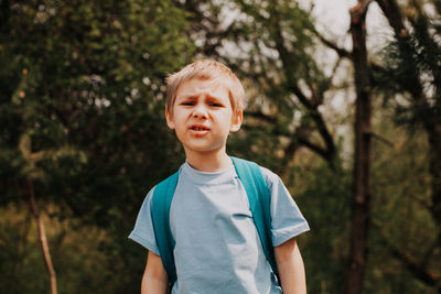 Portrait of boy standing against trees