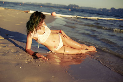 Side view of young woman sitting on beach