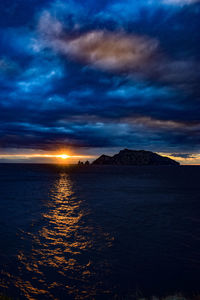 Scenic view of sea against dramatic sky during sunset