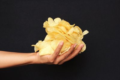 Close-up of hand holding ice cream against black background